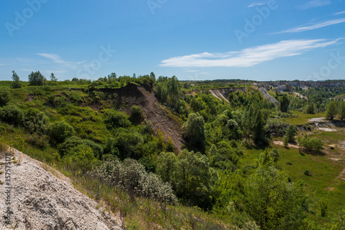 A beautiful summer landscape overlooking an old abandoned quarry and a race track deep in an abandoned quarry. Blue skies and clouds, trees and lots of greenery everywhere. High quality photo