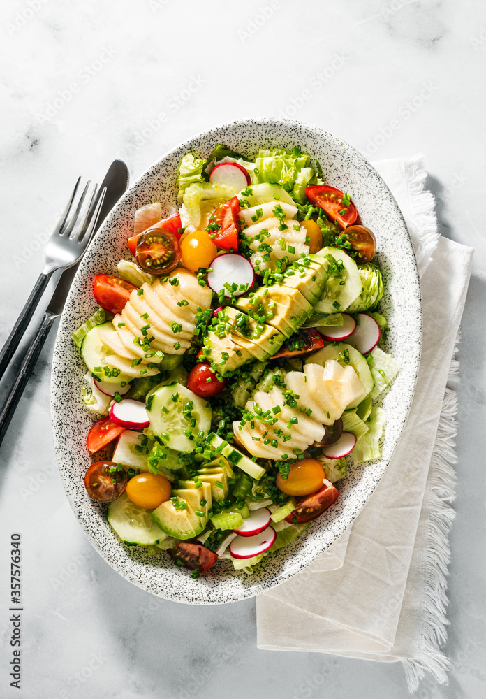 Φωτογραφία summer fresh salad of fruits and vegetables in an oval plate on a table with cutlery