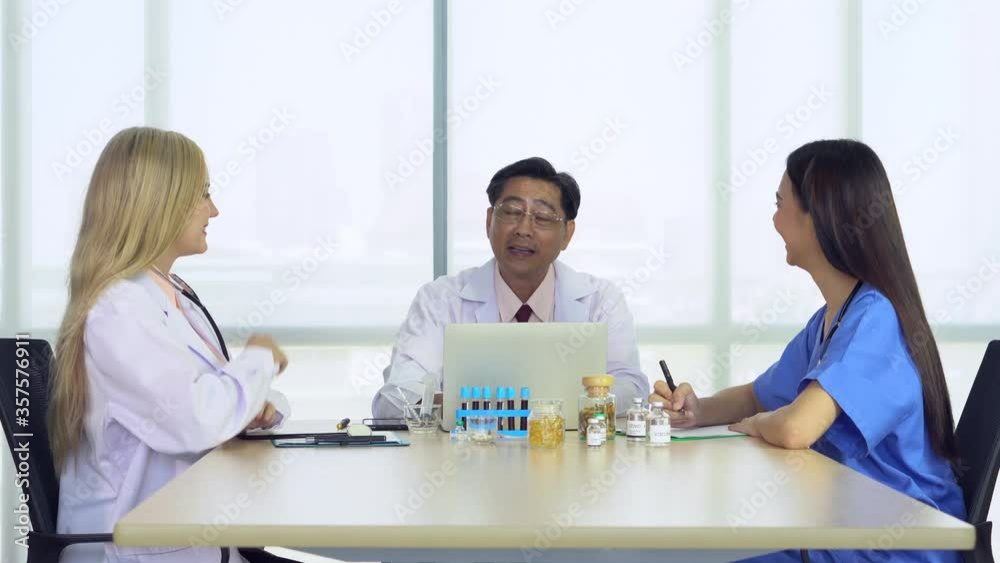 In conference room in hospital, senior doctor discussed about new treatment for patient with young caucasian and asian medical students. medical school and teamwork concept In conference room in hospital, senior doctor discussed about new treatment for patient with young caucasian and asian medical students. medical school and teamwork concept