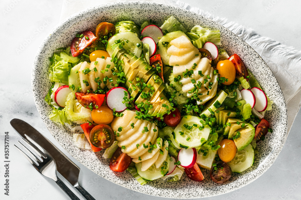 Φωτογραφία summer fresh salad of fruits and vegetables in an oval plate on a table with cutlery