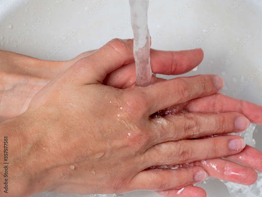 the girl washes her hands under a stream of water. Daily care and hygiene rules that protect against viruses and bacteria