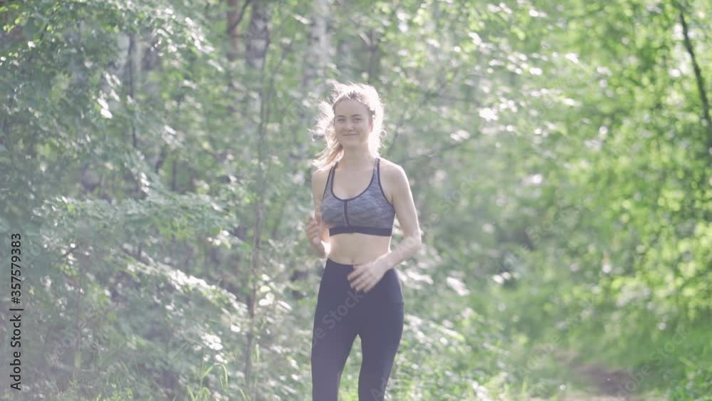 Slender sexy woman goes in for sports in the park. Morning run through the forest. Breasts sway while running Slender sexy woman goes in for sports in the park. Morning run through the forest. Breasts sway while running