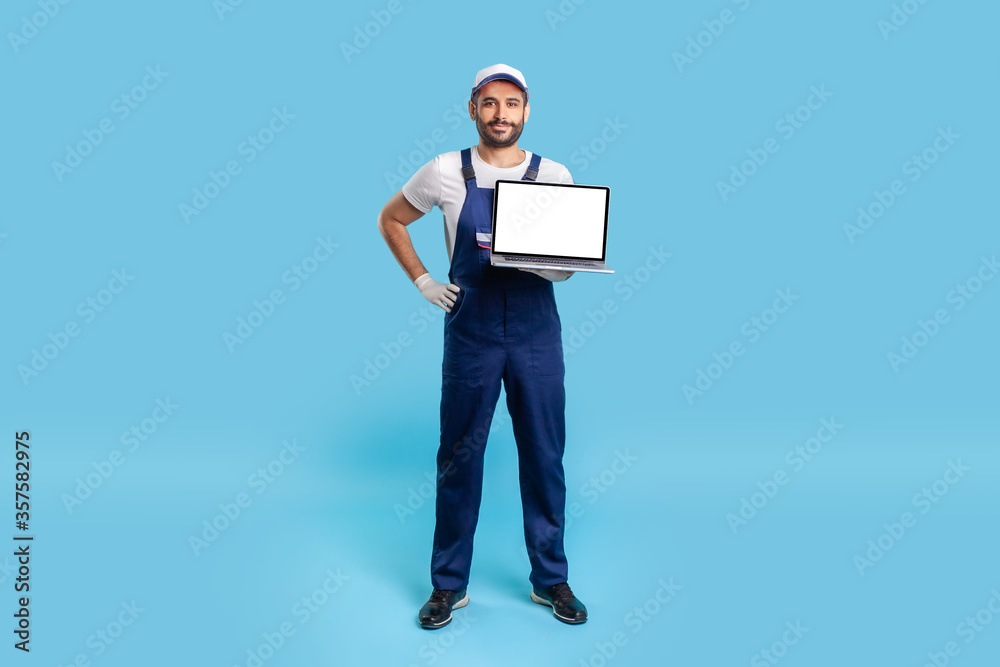 Full body portrait of confident professional expert repairman in workwear holding laptop with mock up blank display, empty place for advertise, message or repair service order. studio shot isolated Full body portrait of confident professional expert repairman in workwear holding laptop with mock up blank display, empty place for advertise, message or repair service order. studio shot isolated