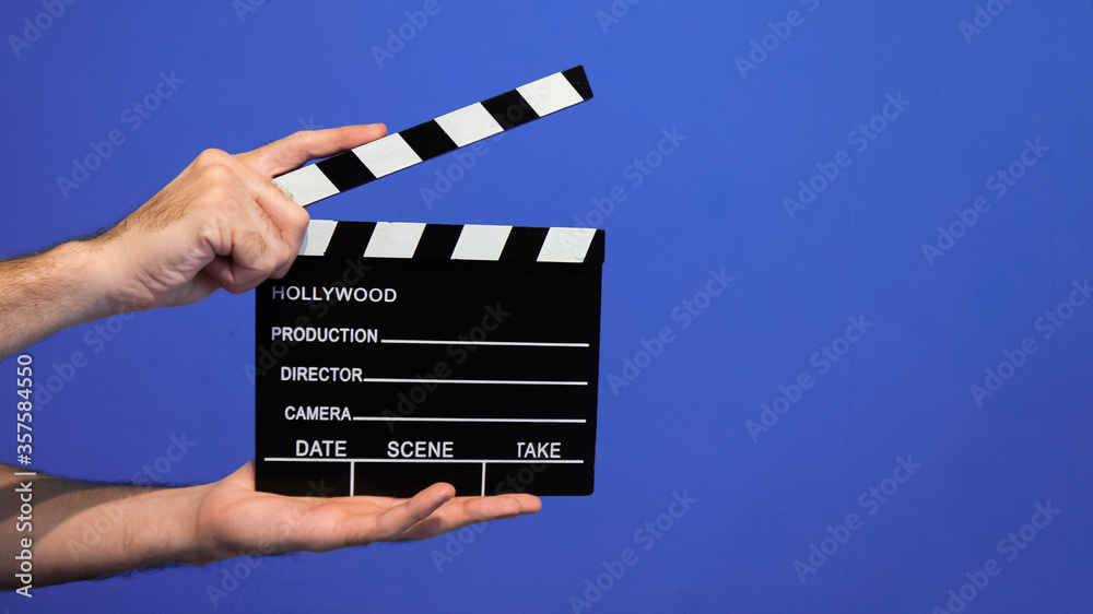 Obraz premium hand holding movie clapper board on blue background