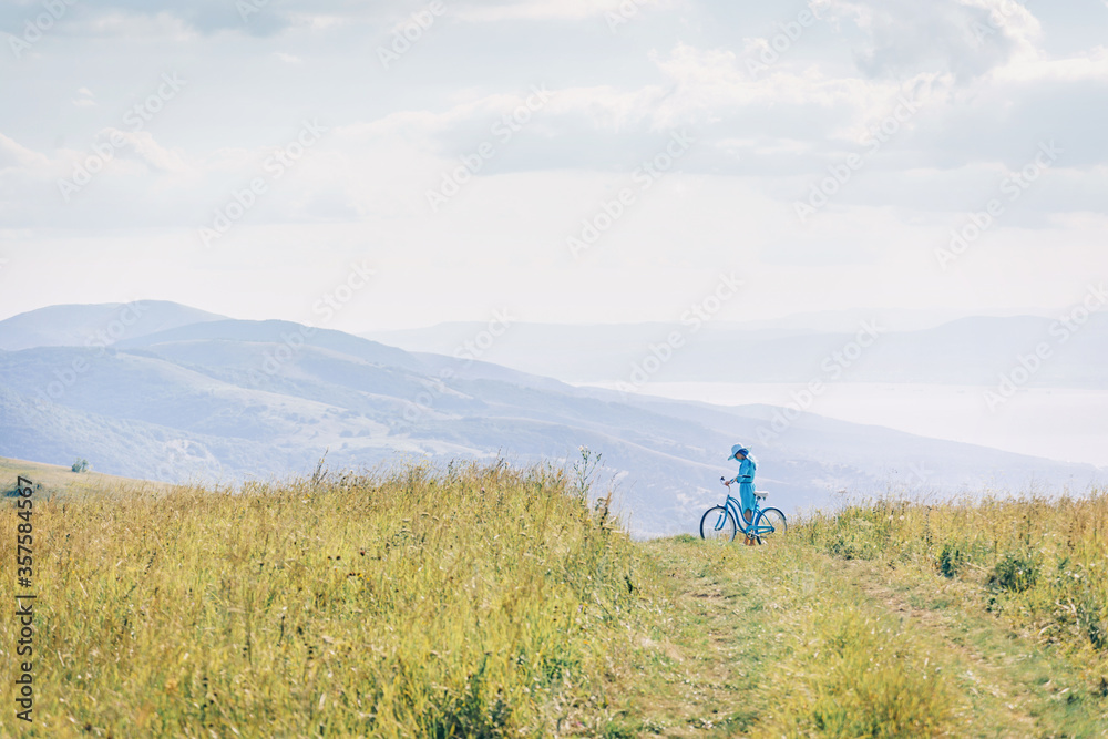 Woman walking on path among green grass meadow.