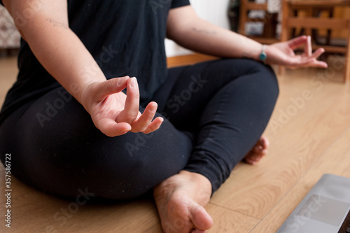 close-up of a woman practicing yoga at home. Focus on her right hand.