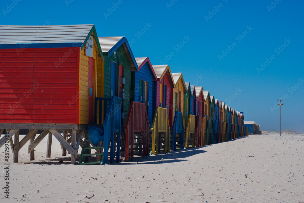 Naklejka premium Colorful beach houses and blue sky in Muizenberg Beach in South Africa. Multi-colored beach huts in Western Cape