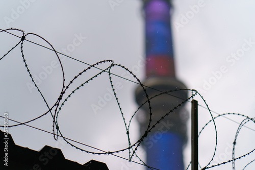 Ostankino tv tower details  through barbed wire in rainy sky. The high technology in everyday life. Telephoto lens. Coronavirus pandemic photo