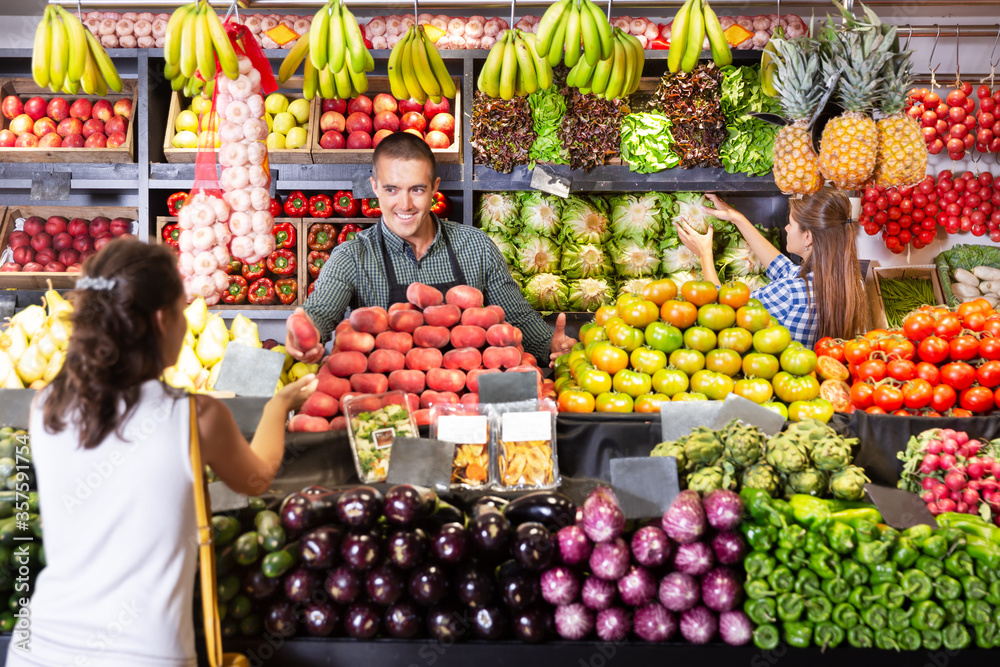 Shop assistants selling fruits and vegetables to buyer