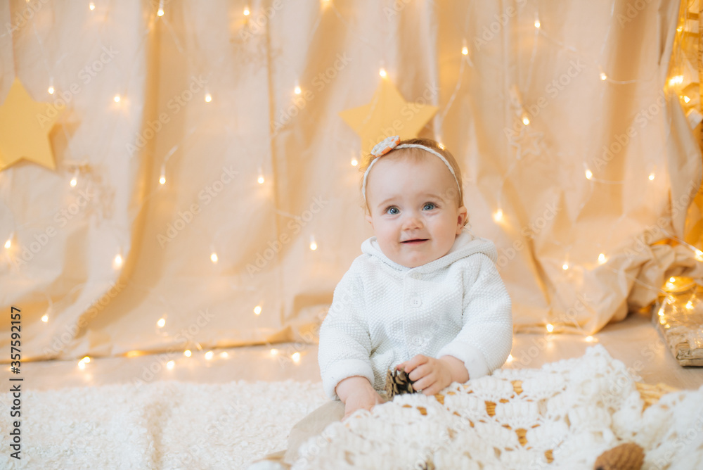 Little cute girl 1 year old in a light knitted sweater and bandage with a flower on her head sits and playing with fir cones. Festive mood. Merry Cristmas
Little cute girl 1 year old in a light knitted sweater and bandage with a flower on her head sits and playing with fir cones. Festive mood. Merry Cristmas