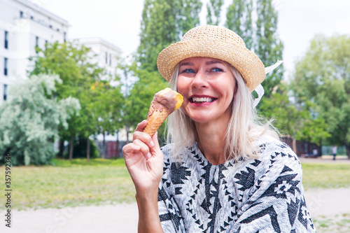  blond woman eating ice cream at a park
