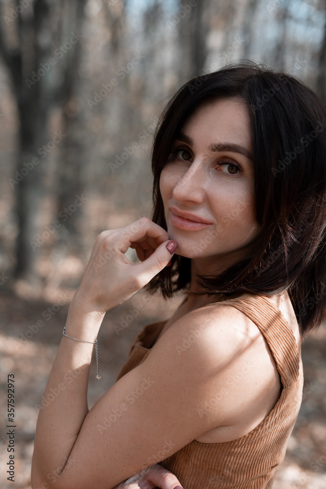 A beautiful young woman holds her hand at her face and looks into the camera. Portrait. Sunny summer day. Close up A beautiful young woman holds her hand at her face and looks into the camera. Portrait. Sunny summer day. Close up