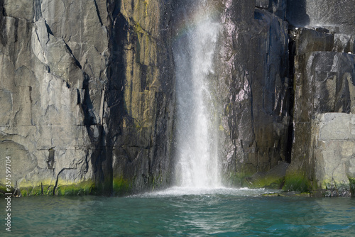 Cliff with a waterfall and turquoise water. This place is called "Alkefjellet". It is a bird cliff.