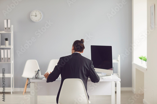 A man in a black suit sitting at the table works with papers in the office. © Studio Romantic