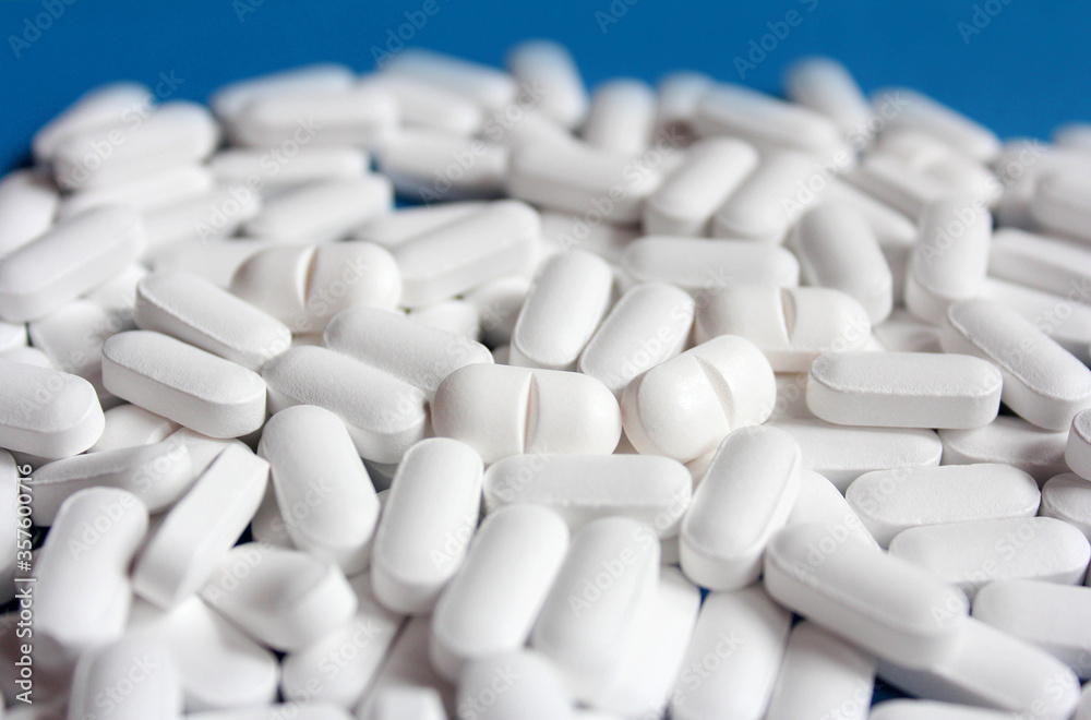 White pills on a blue background, close up