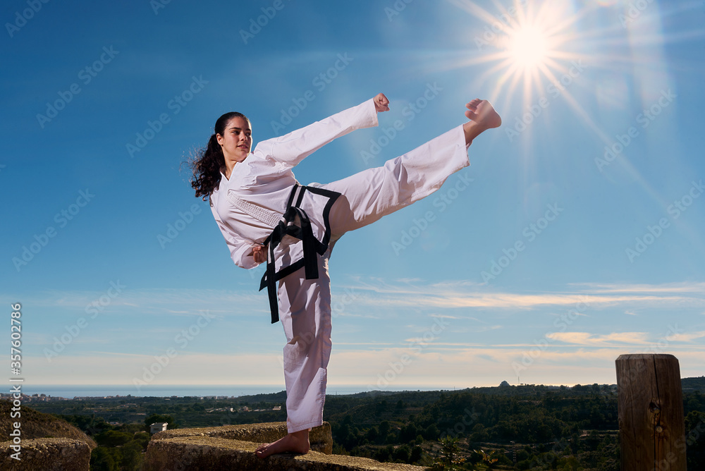 Young black belt girl kicks towards the sun. Taekwondo martial art. Young black belt girl kicks towards the sun. Taekwondo martial art.