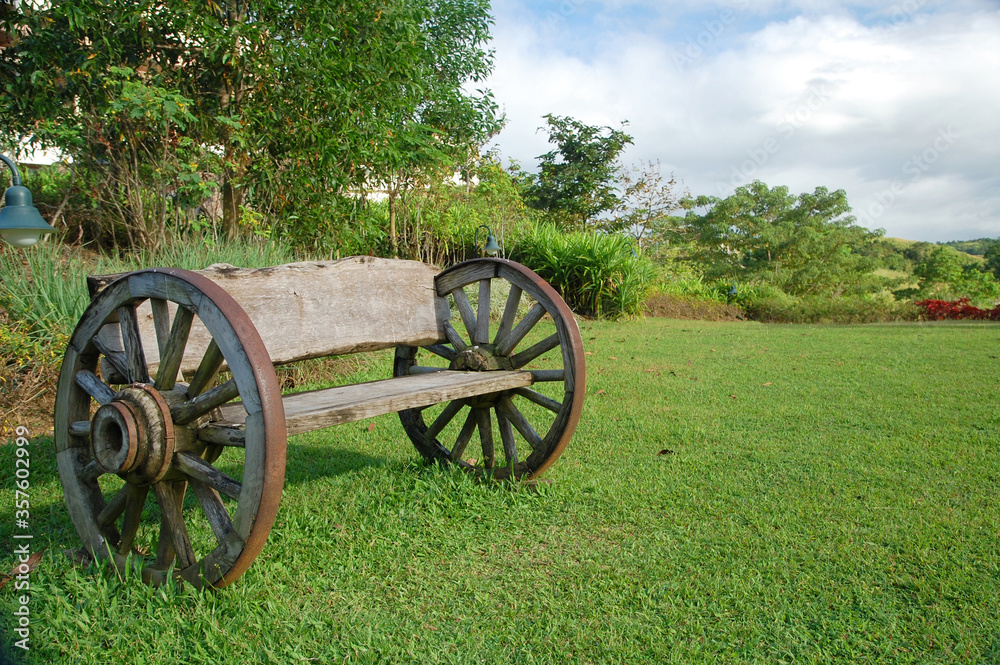 Wooden bench with wheels placed in green grass
