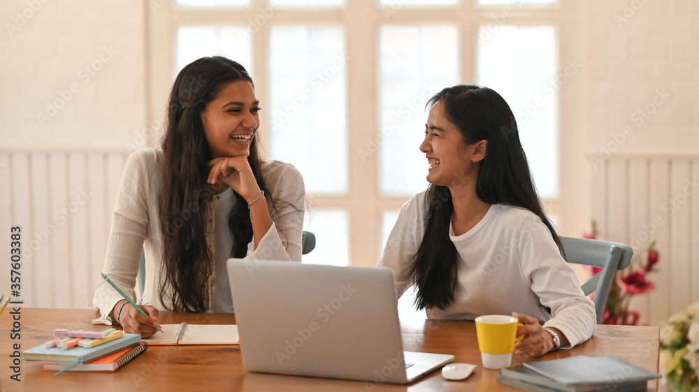 University students are sitting together in front of a computer laptop at the working desk. University students are sitting together in front of a computer laptop at the working desk.