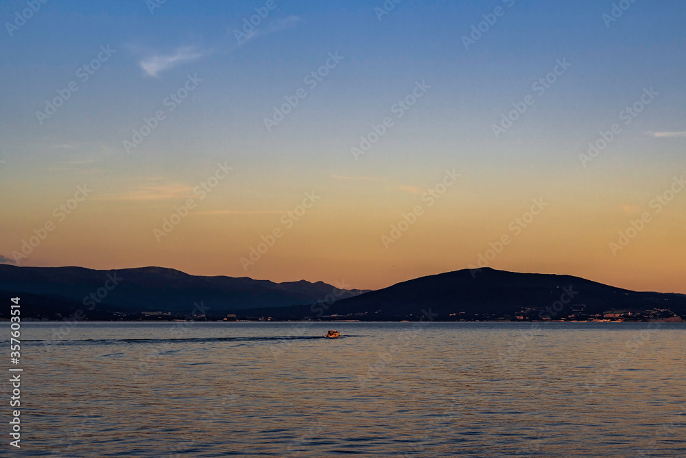 Pleasure boat floating in the bay during a summer sunset.