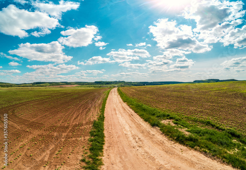 Rural landscape with beautiful sky  farmland  aerial view. View of dirt road through the plowed field in spring