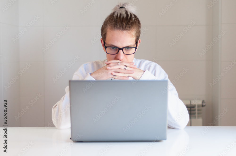 Young adult with glasses working at home with laptop Young adult with glasses working at home with laptop