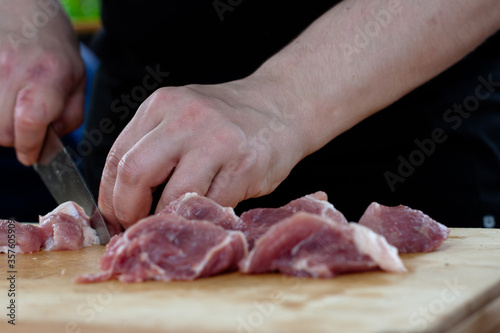 cutting meat into pieces with a knife on a wooden Board. the cook cuts the meat.