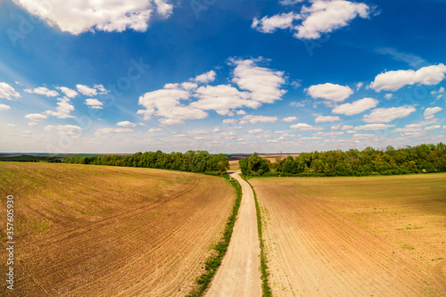 Rural landscape with beautiful sky  farmland  aerial view. View of dirt road through the plowed field in spring