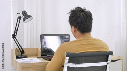 Asian male working from home communicate via video conferenc using laptop in the bedroom photo