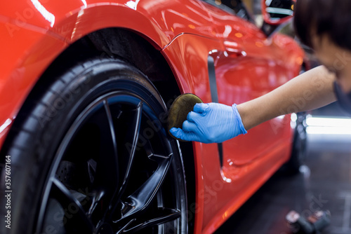 Car service worker polishing car wheels with microfiber cloth. © romaset