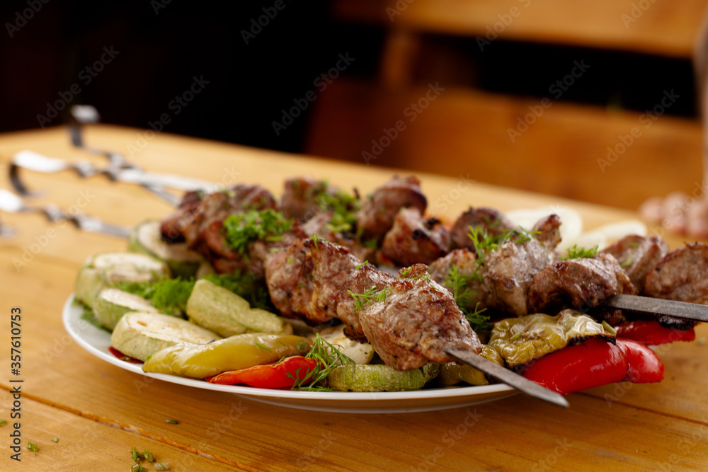a tray with meat on skewers sprinkled with herbs on grilled vegetables