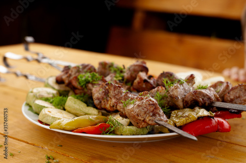 a tray with meat on skewers sprinkled with herbs on grilled vegetables
