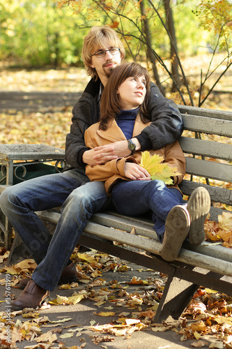 A young couple in love is sitting on a Park bench. Bright and warm autumn day.