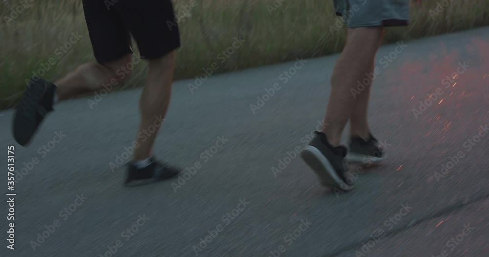 Back view of two sportsmen jogging synchronously on walkway in evening Back view of two sportsmen jogging synchronously on walkway in evening