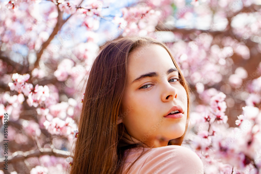 Young girl posing near blossom cherry tree with pink flowers Young girl posing near blossom cherry tree with pink flowers
