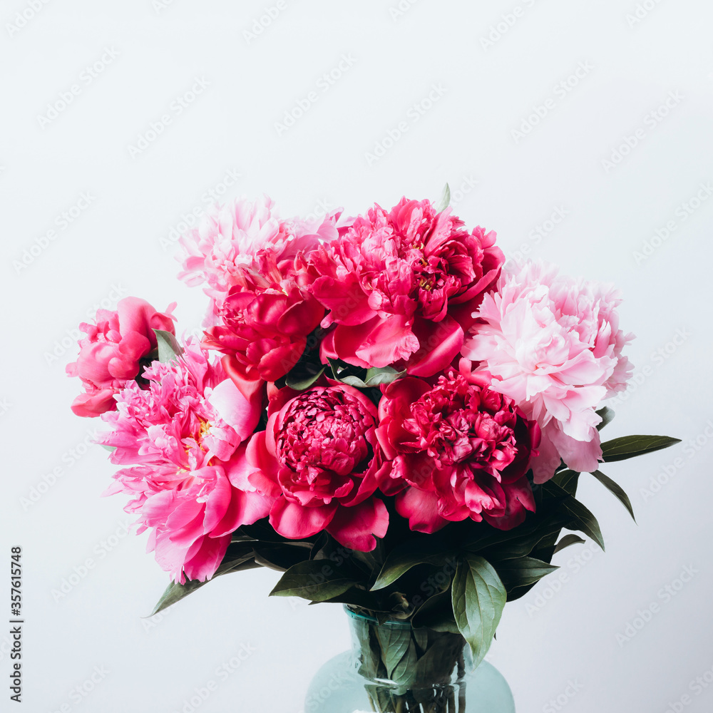 Beautiful peonies bouquet in glass vase on concrete wall background. Soft focus, front view Beautiful peonies bouquet in glass vase on concrete wall background. Soft focus, front view