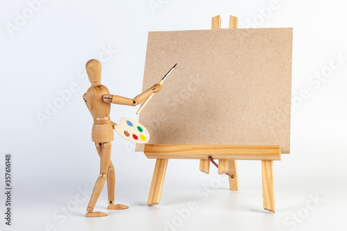 Wooden man paints a picture on easel, space to insert text or design.
