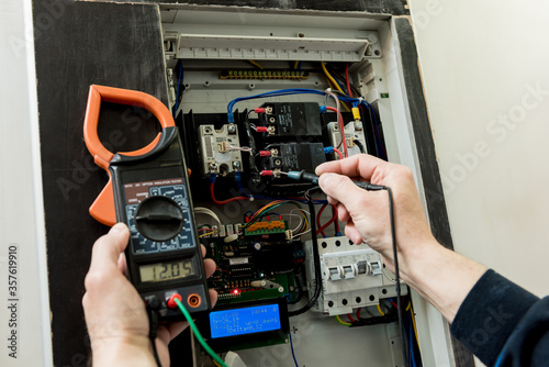 The man is repairing the switchboard voltage with automatic switches.