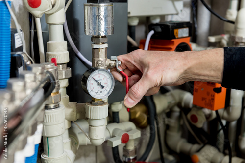 Heating engineer fixing modern heating system in boiler room. 