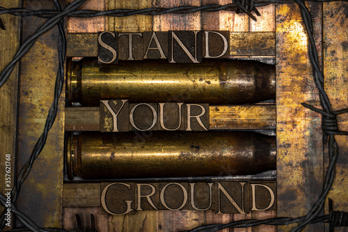 Stand Your Ground text formed with real authentic typeset letters on vintage textured silver grunge copper and gold background