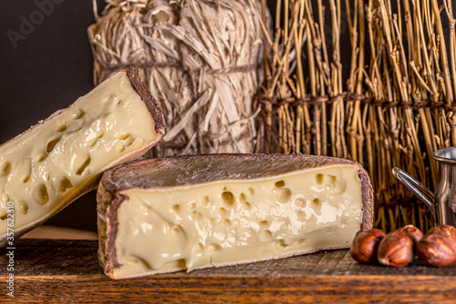 French cheese Saint Nectaire rustic collection delicious. Black background. photo