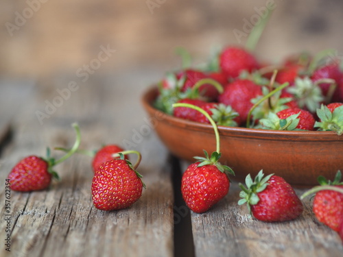 Fresh red strawberries in an clay plate on a wooden background.Summer berry background.