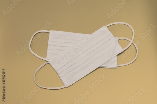 Two white fabric face masks designed to protect the wearer from spreading or acquiring a disease like influenza or corona