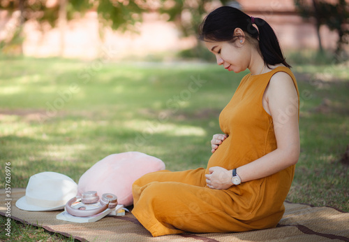 proud pregnant woman in the park. at sunrise with a warm light in the background.