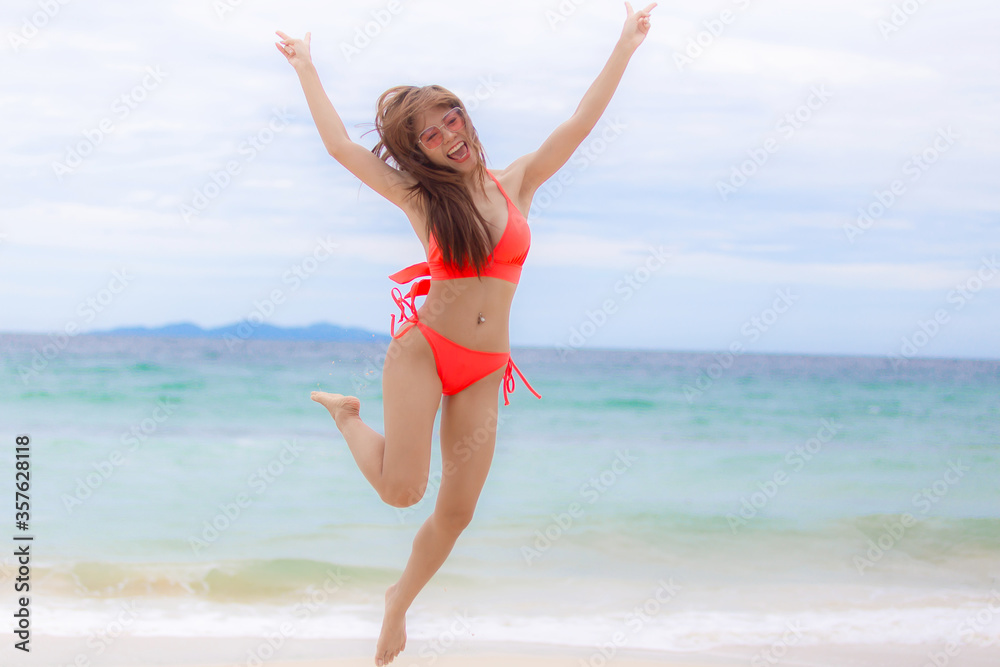 young beautiful sexy woman wearing red bikini and relaxing on the white sandy beach near the waves of blue on tropical beach background near ocean / Summer concept. young beautiful sexy woman wearing red bikini and relaxing on the white sandy beach near the waves of blue on tropical beach background near ocean / Summer concept.
