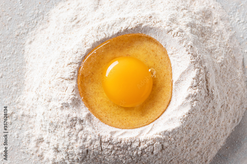 Fresh egg in a heap of wholemeal flour on a marble table. healthy diet concept. close-up. top view. horizontal image. Fresh egg in a heap of wholemeal flour on a marble table. healthy diet concept. close-up. top view. horizontal image.