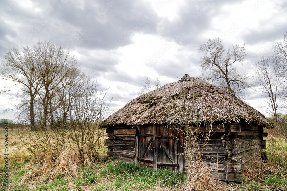 Kudrichi, Belarus 04/27/2020: Old houses and sheds with a roof covered with reeds using old-fashioned technology in the Polesie region in the south-west of Belarus. Kudrichi, Belarus 04/27/2020: Old houses and sheds with a roof covered with reeds using old-fashioned technology in the Polesie region in the south-west of Belarus.