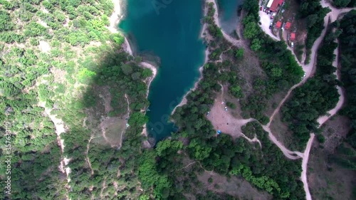 Epic motion lapse lift off above lake Tsivlou in Greece. Green waters surrounded by pine trees and clouds casting moving shadows. Bird-eye view shot. photo