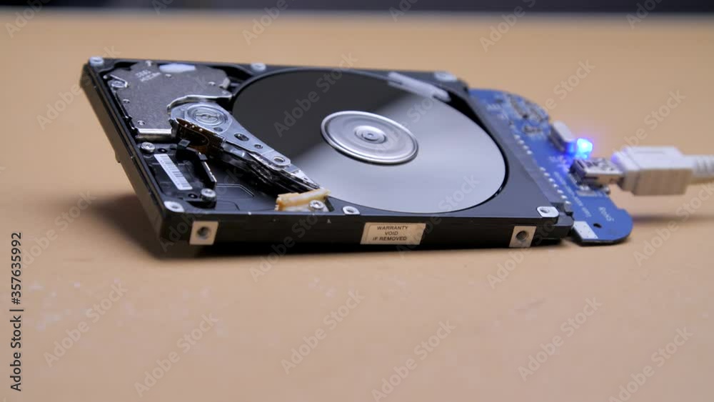 Work of hacked open hard drive inside. Hacker breaks sensitive data from a hard drive. Repair hard disk drive with spinning platter. Close-up of magnetic head. Internal Structure of HDD lies on table. Work of hacked open hard drive inside. Hacker breaks sensitive data from a hard drive. Repair hard disk drive with spinning platter. Close-up of magnetic head. Internal Structure of HDD lies on table.