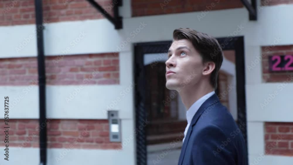 Businessman in white shirt walks down the street in blue jacket.