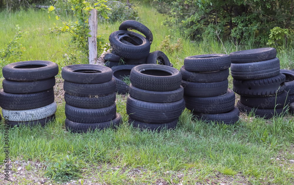 Damaged and worn old black tires on a stack. Damaged and worn old black